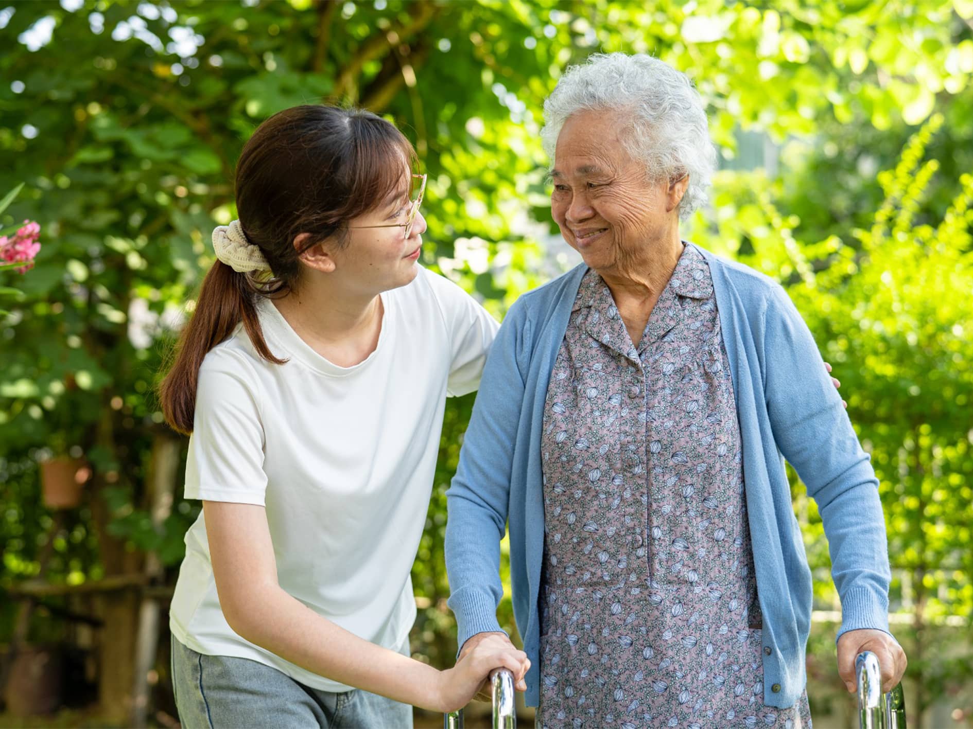 Social worker woman helps elderly woman walk.