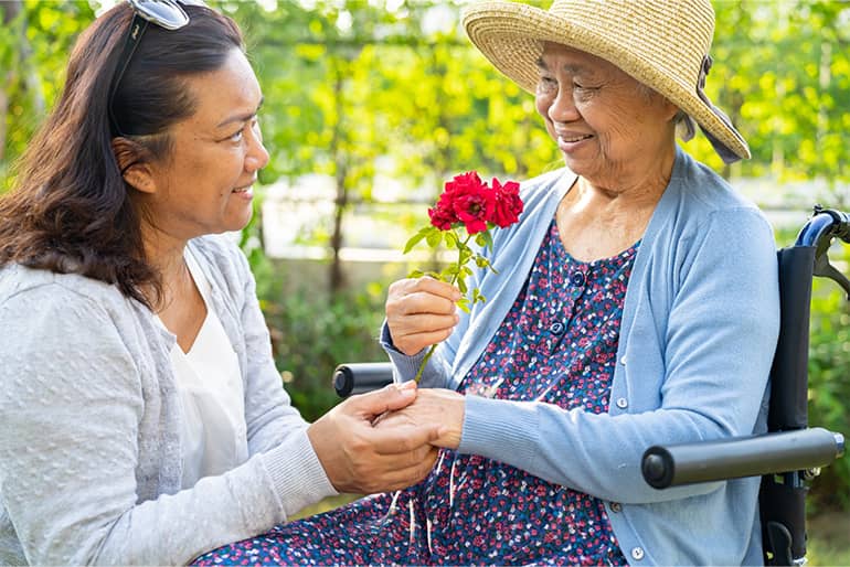 A caregivier helps an elderly woman in a wheelchair