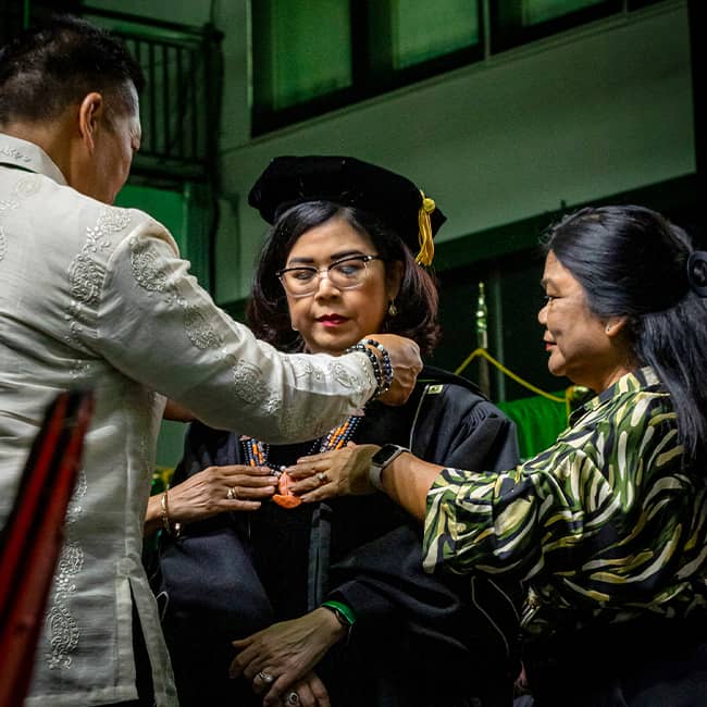 Dr. Anita's husband presents University Collar to her at Calvo Fieldhouse