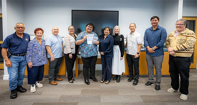 Christian Gyles Ramos poses with congratulatory letter and SBPA faculty