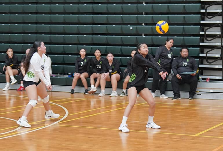 Student athlete in black jersey holds arms out to bump volleyball