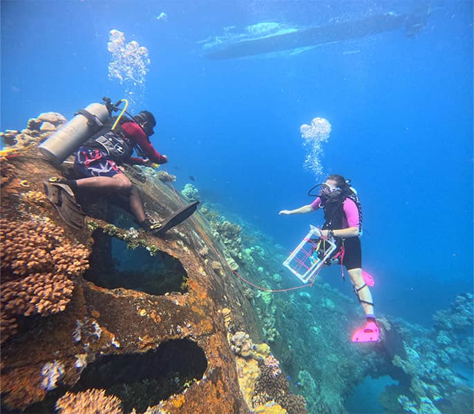 Underwater photo of Kalle Applegate-Palmer and Chioshy Topias surveying shipwreck in scuba gear