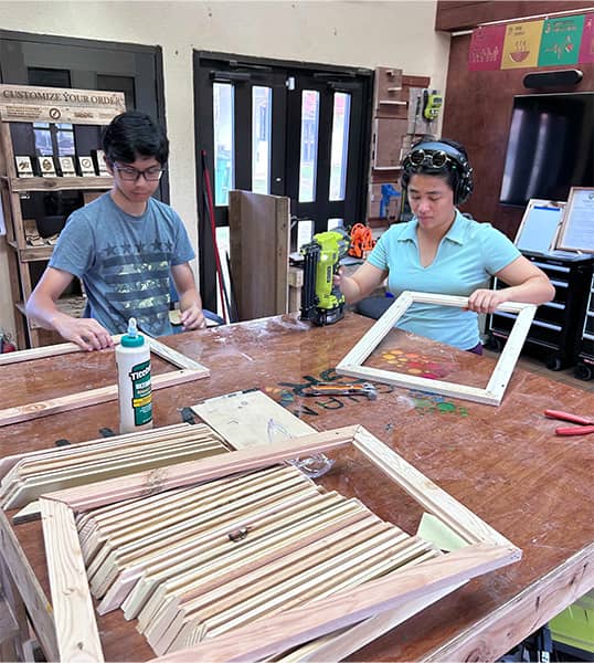 Members of G3 create frames using pallet wood for featured works of art