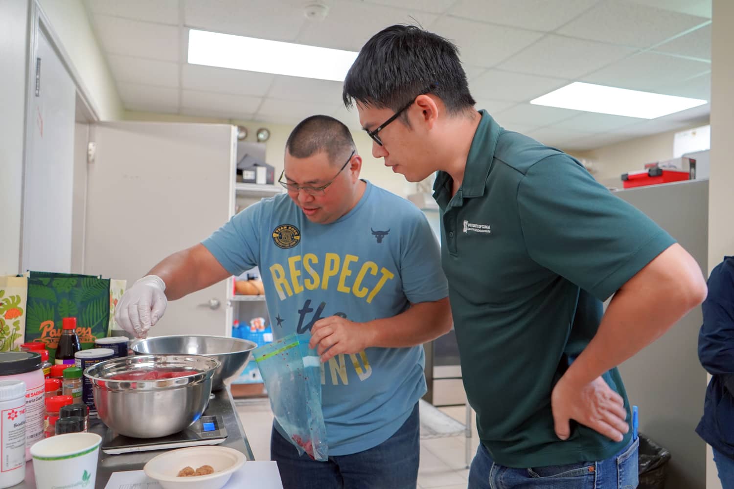 UOG meat scientist Leo Liu watches as a participant seasons pork at BBQ Bootcamp workshop