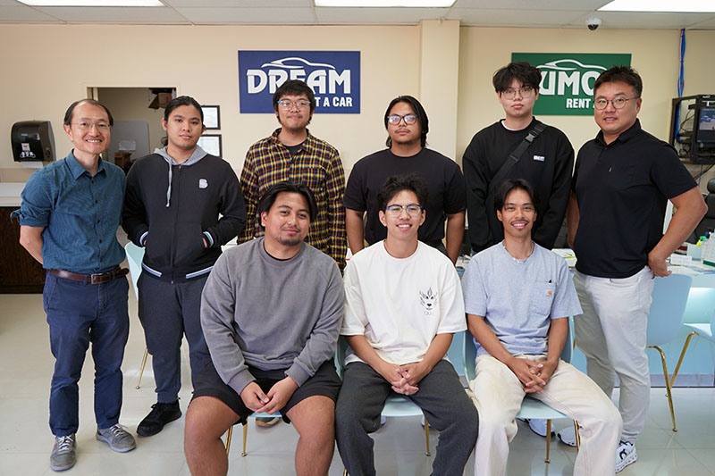 A group of students posed for a photo at a car rental agency