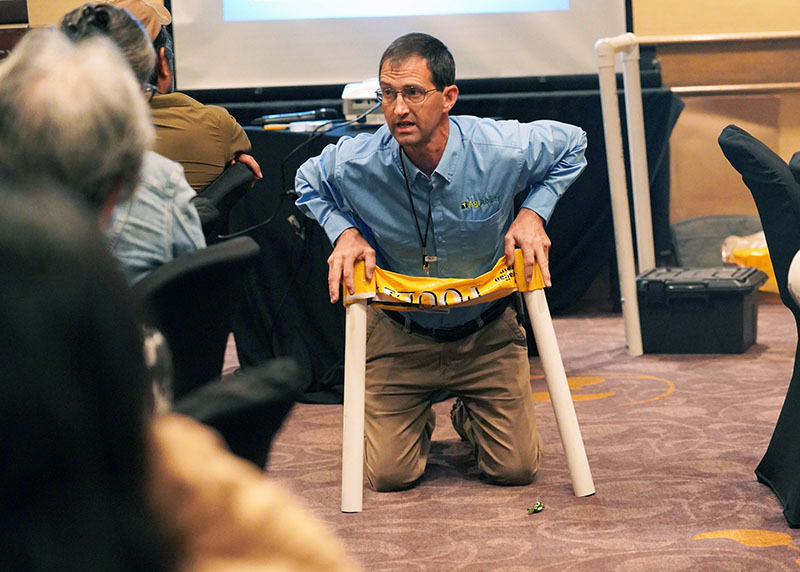 Photo of Ned Stoller demonstrating a homemade assistive aid 