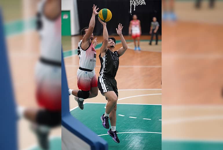 Opposing team members reach for basketball as one takes a shot