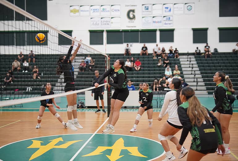 athletes block a spike from opposing team in lady triton volleyball league