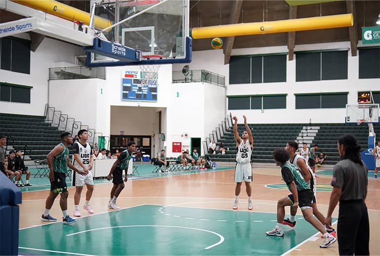 Men's basketball player in white jersey does free throw while other players surround