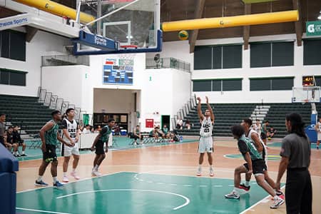 Basketball team member in white jersey does free throw with other players surrounding