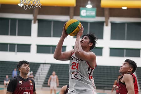 Athlete shoots basketball while flanking opponents watch