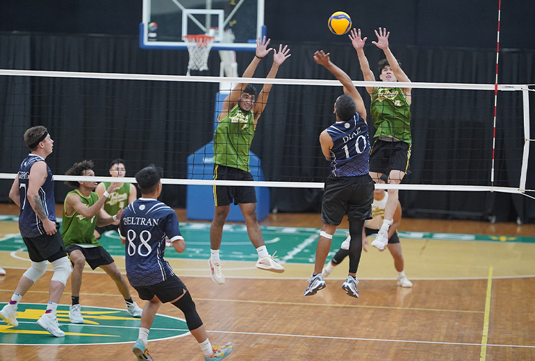 Bombers play defense, attempting to block the volleyball.