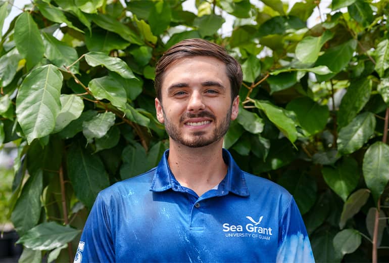 Garett O'Donnell poses for a photo in front of large green outdoor plant