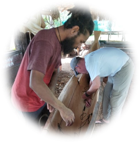 Photo of two students carving a canoe